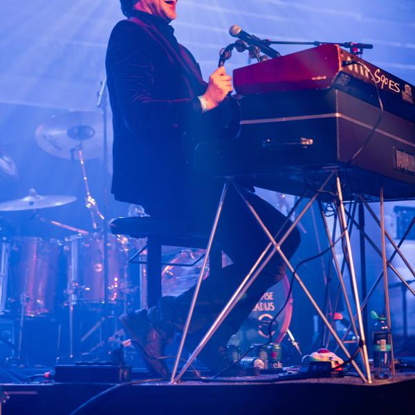 Muzikant achter een keyboard in blauw licht